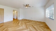 Located in Royal Palm Beach, FL, this two-story, 4-bedroom, 3-bathroom home offers a clean, modern aesthetic throughout. The ground floor houses the kitchen and living area, hallways, a bathroom, and an attached garage. The kitchen stands out with high-gloss white upper cabinetry, warm wood-toned lower cabinets, white quartz countertops, a stainless steel undermount sink, and a stainless steel dishwasher, all illuminated by natural light from a window with slatted blinds. A consistent theme of light herringbone-patterned wood flooring runs throughout both floors, lending warmth and visual interest to every room. The upper floor accommodates all four bedrooms, additional bathrooms, two closets, and connecting hallways. The generously sized primary bedroom features a ceiling fan with light fixture and natural light from a window, while the walk-in closet offers wrap-around wire shelving for ample storage. The bathrooms are finished with large-format subway tile, including a glass-enclosed shower with a mosaic tile floor. Each bedroom is bright and well-proportioned, fitted with ceiling fans and windows offering outdoor views. The attached garage provides a clean, functional space with an automatic opener and electrical panel. The home presents a bright, neutral palette throughout.