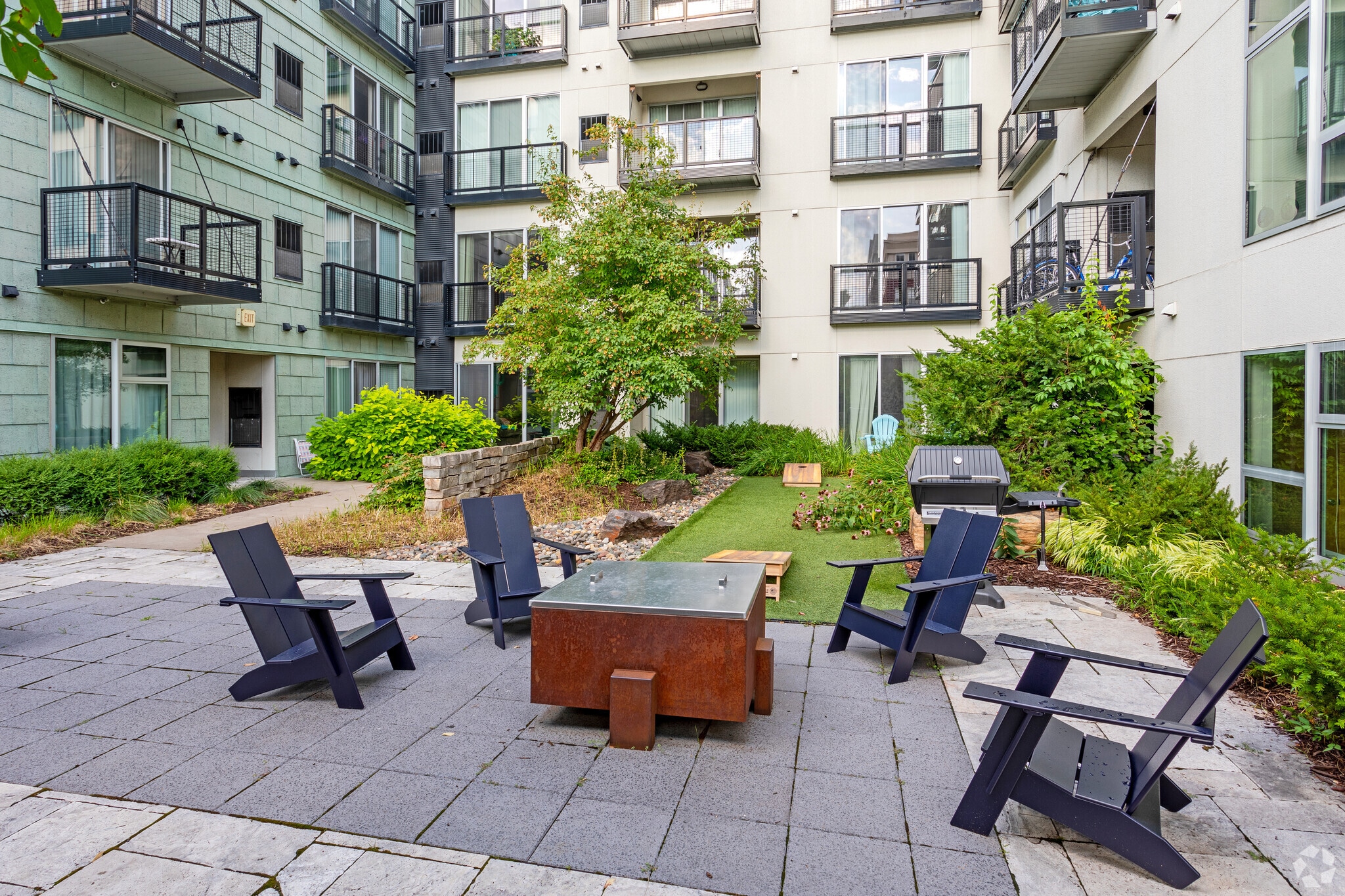 Outdoor courtyard with seating, fire pit, and grill.