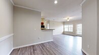 This well-appointed 4-bedroom, 2-bathroom home in Columbia, SC offers a thoughtfully designed single-floor layout that balances comfort and functionality. The open-concept living and dining area serves as the heart of the home, featuring wood-style plank flooring, crown molding, a ceiling fan, and large windows that invite an abundance of natural light. A glass door provides direct outdoor access, enhancing the sense of openness. The kitchen is efficiently laid out in a galley style, showcasing rich cherry wood cabinetry, dark granite-style countertops, a breakfast bar pass-through, and black appliances including a full-size refrigerator and range. The four bedrooms are carpeted for comfort, with several rooms featuring walk-in closets equipped with built-in shelving systems. The primary bedroom is generously sized, offering ample space for furnishings. Both bathrooms include vanities with warm wood cabinetry, full tub-shower combinations, and wood-style flooring. A dedicated laundry area with washer and dryer hookups adds everyday convenience. Neutral warm-toned walls throughout create a clean, cohesive aesthetic that complements the home's practical and inviting design.