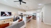 This single-story home in Huntsville, Alabama offers a thoughtfully designed open-concept layout that connects the living room, dining area, and kitchen into one cohesive, comfortable space. Vaulted ceilings rise dramatically over the kitchen and living area, enhancing the sense of openness, while recessed lighting and a ceiling fan contribute to both function and style. Light-toned wood-look flooring runs throughout, lending a clean, consistent aesthetic to the entire home.

The kitchen serves as a centerpiece of the main living space, featuring white shaker cabinetry, granite countertops, stainless steel appliances, and a peninsula island with seating for three. Pendant lighting above the island adds a modern touch. The living room benefits from large windows that bring in natural light, and a front entry door opens directly into this welcoming space.

The spacious primary bedroom includes tall ceilings, multiple windows, a ceiling fan, and access to a walk-in closet with wire shelving. The en-suite primary bathroom offers a double-sink vanity with granite countertops, white cabinetry, and matte black fixtures. The second bedroom is well-proportioned and bright. The second bathroom features a single granite-topped vanity and a tub-shower combination, maintaining the same refined finishes found throughout the home.