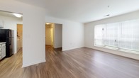 This single-floor residence at 1100 Townsend Blvd in Fredericksburg, Virginia offers a clean, functional layout with a bright and neutral interior palette throughout. The living area is finished with warm wood-look flooring and features a large window that allows natural light to fill the space, creating an open and airy atmosphere. A ceiling fan adds comfort, and the room flows conveniently toward the kitchen and adjoining spaces.

The galley-style kitchen is well-appointed with white cabinetry, granite-look countertops, a double basin sink, and black appliances including a refrigerator and range. A dedicated walk-in pantry or storage closet is accessible directly from the kitchen, providing ample organizational space.

The bedrooms are carpeted for comfort and each includes a window with blinds offering natural light and privacy. The layout as seen in the dollhouse view reveals a thoughtfully connected floor plan with clear separation between living and sleeping areas.

Two full bathrooms serve the residence, each featuring a tub-shower combination, toilet, and vanity with storage. Both bathrooms are finished with wood-look flooring and crisp white fixtures, contributing to a clean and well-maintained aesthetic. Overall, the space presents a practical and comfortable living environment in a convenient Fredericksburg location.