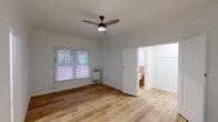 Located at 132 S Westmoreland Ave in the heart of Los Angeles' Koreatown neighborhood, this single-floor unit offers a clean, functional layout with thoughtful updates throughout. The main living area is bright and open, featuring warm light wood-style flooring and crisp white walls that create an airy atmosphere. A ceiling fan provides year-round comfort, while a wall-mounted heating unit ensures reliable warmth. Natural light filters in through a window fitted with horizontal blinds, adding to the welcoming feel of the space. An open doorway connects the living area directly to the kitchen, which is outfitted with sleek gray cabinetry, a double-basin stainless steel sink, granite-style countertops, and tile flooring — offering both style and practicality. The bedroom continues the cohesive aesthetic with matching wood-style flooring, a ceiling fan, and direct access to a full bathroom and a generous walk-in closet. The walk-in closet features built-in shelving and hanging rods, maximizing storage potential. The bathroom is finished with warm earth-tone ceramic tile on both the floors and shower surround, complemented by a full soaking tub, vanity, and a small window for ventilation. The overall layout is compact yet efficient, making excellent use of every area of the space.