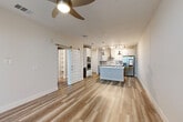 Located in Melbourne, FL, this thoughtfully designed one-bedroom, one-bathroom residence offers a cohesive blend of modern finishes and functional living spaces across a single floor. Light-toned wood-look flooring flows throughout the main areas, enhancing the open, airy feel of the layout.

The open-concept living and kitchen area forms the heart of the home. The kitchen is a standout feature, equipped with white shaker cabinetry, a decorative tile backsplash, a black electric cooktop, stainless steel appliances including a French door refrigerator and dishwasher, and a center island with a farmhouse-style sink and pendant lighting above. Track lighting and ceiling fans add both practicality and style.

A charming sliding barn door connects the living area to a hallway leading to the bedroom and closet. The bedroom is generously sized, finished with plush carpeting, a ceiling fan, and windows that bring in natural light. The walk-in closet features built-in shelving and organizational systems for ample storage.

The bathroom is well-appointed with a dual-sink vanity, brushed nickel hardware, a large mirror, and a glass-enclosed walk-in shower with tile surround. A dedicated laundry room includes cabinetry with quartz countertops for added convenience. The overall ambiance is clean, modern, and move-in ready.
