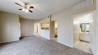 This single-floor residence offers a practical and comfortable layout across two bedrooms, two bathrooms, a dedicated laundry area, and three closets. The open-concept living, dining, and kitchen area forms the heart of the home, featuring plush carpet flooring, a ceiling fan with light fixture, and large windows that invite abundant natural light and create an airy atmosphere. A private entry door adds an additional layer of convenience to the living space.

The kitchen is a standout feature, boasting a U-shaped layout with crisp white cabinetry, light quartz-style countertops, a double-basin sink with a modern faucet, and white appliances including a range and over-the-range microwave. Light wood-style flooring runs throughout the kitchen, complementing the clean, bright aesthetic.

The primary bedroom is a well-sized retreat with carpet flooring, a ceiling fan, and multiple windows offering natural light. Both bedrooms include closet storage, with the primary featuring a spacious walk-in or reach-in closet. The two full bathrooms are finished with white vanity cabinetry, granite-style countertops, large mirrors, and tub/shower combinations with light wood-style tile flooring. The neutral, warm color palette and textured ceilings are consistent throughout, lending the home a cohesive and inviting character.