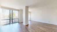 Located at 808 Fourth Avenue in San Diego's vibrant Cortez Hill neighborhood, this single-floor unit offers a clean, modern aesthetic throughout. The open living area is immediately welcoming, featuring warm wood-style flooring that extends seamlessly across the entire space. A defining architectural element is the central structural column that anchors the living area, adding visual character while preserving an open, airy feel. Large floor-to-ceiling sliding glass doors with vertical blinds line multiple walls, flooding the interior with abundant natural light and offering views of the surrounding urban streetscape.

The galley-style kitchen is efficiently designed with white cabinetry reaching toward the ceiling, granite-look countertops, a built-in oven, and a full-size refrigerator, providing ample storage and functionality. The bathroom is clean and well-appointed, featuring a full tub-shower combination, a granite-topped vanity with an integrated sink, and the same wood-style flooring found throughout the unit.

Two closets provide generous storage solutions, complementing the practical layout. The neutral white walls and consistent flooring create a bright, cohesive ambiance that lends itself well to a variety of interior styles. The presence of multiple exterior-facing doors offers excellent ventilation and connectivity to the outdoors, enhancing the overall sense of openness in this well-located San Diego residence.