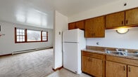 Located at 525 S Church St in Decatur, Illinois, this single-floor unit offers a practical and straightforward layout suited for everyday living. The space is organized to provide clear separation between the kitchen, living areas, and private rooms, as seen in the floor plan.

The kitchen is equipped with warm honey-toned wood cabinetry both above and below the granite-look countertops, a double-basin sink, a white electric range with overhead ventilation, and a full-size refrigerator. Tile flooring runs through the kitchen and entry areas, and a window with wood trim brings in natural light. A baseboard heating unit is also present. An adjacent wall-unit air conditioner provides cooling flexibility.

The living and bedroom areas feature neutral carpeting and are trimmed with warm wood baseboards and door frames that carry a consistent aesthetic throughout. Ceiling fans are installed in the bedrooms, and multiple gridded windows with wood surrounds allow natural light to enter. Baseboard heaters are found in these rooms as well.

The bathroom is cleanly finished with tile flooring, a pedestal sink, a mirrored medicine cabinet, and a full tub-shower combination with a white surround. The entry foyer features tile flooring and a solid wood door. Overall, the unit presents a clean, functional environment with consistent warm wood accents throughout.