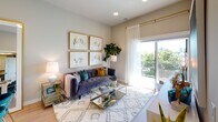 This well-appointed single-floor residence showcases a cohesive modern design throughout, with light hardwood-style flooring, neutral wall tones, and contemporary finishes tying each space together seamlessly. The open-concept kitchen is a standout feature, outfitted with dark navy cabinetry, white quartz countertops, a subway tile backsplash, stainless steel appliances including a french door refrigerator, and a peninsula island with an undermount sink — ideal for both cooking and casual entertaining. The adjacent dining area provides a natural transition, enhanced by a large gold-framed mirror that amplifies the sense of space and light. The living room is bright and welcoming, benefiting from oversized sliding glass doors that open to a private balcony with open outdoor views, allowing abundant natural light to fill the space. The bedroom continues the refined aesthetic, featuring plush carpeting, a ceiling fan, and large windows with balcony access that frame views of the surrounding greenery and cityscape beyond. The full bathroom is generously proportioned, offering a dual-sink vanity with dark cabinetry and quartz countertops, a large wall mirror, and a glass-enclosed walk-in shower with elegant marble-style tile surround. Throughout, the design balances style and functionality with thoughtful attention to detail.