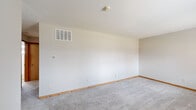 Located at 5795 N Meadows Blvd in Columbus, Ohio, this single-floor, 2-bedroom, 1-bathroom unit offers a practical and functional layout. The interior features neutral-toned walls throughout, complemented by light gray carpeting with warm wood baseboards that lend a consistent, cohesive look across the living spaces.

The spacious primary bedroom provides generous room for furnishings and features overhead lighting, a ceiling-mounted smoke detector, and built-in HVAC vents. The second bedroom includes a louvered bifold closet door, a window unit air conditioner, and a window with natural light overlooking the surrounding neighborhood. Both bedrooms benefit from ample wall space and soft carpeted flooring.

The kitchen is equipped with warm honey-toned wood cabinetry above and below the counter, white tile backsplash, light vinyl plank flooring, and white appliances including a gas range and full-size refrigerator. The full bathroom features a soaking tub with a shower surround, a toilet, and a distinctive glass block window that allows diffused natural light while maintaining privacy.

Overall, the space presents a clean, move-in-ready environment with a straightforward, efficient layout well-suited for everyday living in Columbus.