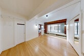 Located at 2205 2nd Ave in Seattle's vibrant Belltown neighborhood, this efficiently designed unit blends historic character with modern updates. Light-toned hardwood floors run throughout the space, lending warmth and continuity across the living room and into the kitchen area. Exposed brick columns and a brick accent wall serve as striking architectural focal points, complemented by white-painted walls and structural ceiling beams that hint at the building's storied past. The open living area benefits from a large picture window, allowing natural light to fill the room while providing views of the surrounding cityscape. A baseboard heating unit sits beneath the window, ensuring year-round comfort. The kitchen is thoughtfully appointed with white shaker-style cabinetry, stainless steel appliances including a range and over-the-range microwave, a deep farmhouse sink with a matte black faucet, and a vivid green subway tile backsplash that adds a bold design element. An additional window in the kitchen further brightens the space. The bathroom features floor-to-ceiling white subway tile surrounding a full soaking tub and shower combination, with pebble tile flooring adding a refined touch. Two closets provide practical storage solutions. Wall-mounted sconce lighting adds character throughout.