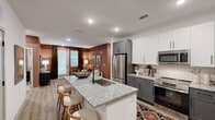 Located at 6615 Cerris Dr in Charlotte, NC, this single-floor, 2-bedroom, 3-bathroom residence offers a thoughtfully designed open-concept layout. The kitchen is a standout feature, showcasing two-tone cabinetry with white upper and gray lower cabinets, a subway tile backsplash, stainless steel appliances, and a granite-topped island with bar seating — all flowing seamlessly into the living area. The living room is warm and inviting, highlighted by a rich terracotta accent wall, large windows with access to an outdoor area, and recessed lighting. Both bedrooms are generously proportioned with plush carpeting, ceiling fans, and ample natural light from large windows. The spacious primary bedroom connects to an en-suite bathroom featuring granite countertops, gray cabinetry with matte black hardware, a glass-enclosed walk-in shower, and access to a roomy walk-in closet with wire shelving. A second full bathroom mirrors the same refined finishes, including a soaking tub. The dedicated laundry room houses a full-sized washer and dryer with overhead shelving for storage. Light wood-tone flooring runs throughout the main living areas, tying together the contemporary and cohesive aesthetic of this well-equipped Charlotte residence.