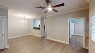 This single-story 2-bedroom, 2-bathroom unit in Gonzales, Louisiana is thoughtfully designed to maximize comfort and functionality. Light wood-style luxury vinyl flooring flows consistently throughout, complemented by crisp white trim, crown molding, and decorative columns that add an elegant touch to the open living areas.

The living room is generously sized, featuring a ceiling fan with light fixture and a chandelier near the dining area, which opens seamlessly to the kitchen via a raised breakfast bar. The kitchen is well-appointed with white cabinetry, dark granite countertops, a mosaic tile backsplash, and black appliances including a range, built-in microwave, dishwasher, and refrigerator.

A central hallway connects the living spaces to the two bedrooms and bathrooms. Each bedroom offers crown molding, ceiling fans, and wood-style flooring. One bedroom features a bright window with natural light. Both bathrooms are finished with white cabinetry, granite-topped vanities, and wood-style flooring; one includes a soaking tub with shower combination, while the other features a walk-in shower. A dedicated laundry area with in-unit washer and dryer hookups adds everyday convenience to this well-appointed home.