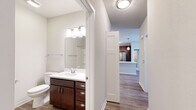 Located on Recreation Drive in West Dundee, Illinois, this single-floor residence offers a thoughtfully designed layout with modern finishes and a cohesive aesthetic throughout. The open-concept living and kitchen area serves as the heart of the home, featuring warm wood-look plank flooring, crisp white walls, and abundant natural light. The kitchen is well-appointed with rich dark espresso cabinetry, white quartz countertops, a central island with a double-basin stainless steel sink, pendant lighting, and a full suite of stainless steel Whirlpool appliances including a refrigerator, range, and microwave. The bedrooms are carpeted for comfort, offering a quiet retreat with ample closet space and natural light from well-placed windows. The primary bathroom is equipped with a generous vanity featuring dark wood cabinetry, a white quartz countertop, a large mirror, and a walk-in glass-enclosed shower with built-in storage. A second full bathroom mirrors the same quality finishes, including a tub-shower combination and matching vanity. A dedicated in-unit laundry area with stacked washer and dryer adds everyday convenience. Panel-style doors and neutral tones throughout create a clean, modern ambiance well-suited for comfortable living.