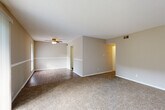 This single-floor residence offers a well-organized layout that flows naturally between its main living spaces. The spacious living area is finished with plush carpet and neutral beige walls, and features a sliding glass door fitted with vertical blinds that floods the room with natural light and provides access to an outdoor space. A ceiling fan with a light fixture adds both comfort and functionality to the adjoining room, which transitions to hardwood-style flooring and connects to the rest of the home.

The kitchen is a standout feature, outfitted with white cabinetry, dark countertops, a classic subway tile backsplash, and stainless steel appliances including a range, dishwasher, and refrigerator. A double-basin sink with a gold-tone faucet completes the clean, contemporary look, all set on warm wood-look flooring.

The bedroom is a comfortable, carpeted retreat with a ceiling fan, a window for natural light, and a textured ceiling overhead. Additional rooms and hallways provide practical connectivity throughout the home.

The bathroom is finished in a crisp, all-white scheme featuring a tiled shower-tub combination, wood-look vinyl flooring, and a drop ceiling, creating a clean and functional space. Throughout the residence, consistent neutral tones, white trim, and well-placed ventilation create a cohesive and welcoming atmosphere.