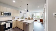 Located at 1143 Main St in Hartford, CT, this thoughtfully designed one-bedroom, one-bathroom unit offers a functional and modern living experience across a single floor. The open-concept kitchen and living area serves as the heart of the home, bathed in natural light from large windows that frame views of the Hartford cityscape and tree-lined streetscape below. The kitchen is outfitted with light wood cabinetry, sleek white quartz countertops, a subway tile backsplash, stainless steel appliances including a gas range and French door refrigerator, and pendant lighting that adds a contemporary touch. Dark hardwood flooring runs throughout the main living area, complementing the neutral, light-toned walls. The living space is bright and inviting, with corner windows that maximize natural light. The bedroom is a well-proportioned retreat featuring plush carpeting, dual windows with city views, and ample room for furnishings. A dedicated closet provides convenient storage. The full bathroom is finished with large-format tile flooring, a wood-tone vanity with white countertop, and a glass-enclosed walk-in shower with white subway tile and matte black fixtures. The overall aesthetic is clean, modern, and cohesive throughout.