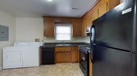 This single-floor residence in Garden Farmingdale offers a practical and comfortable layout designed for everyday living. The kitchen is a functional highlight of the home, featuring warm honey-toned wood cabinetry that extends to the ceiling, providing generous storage throughout. Dark countertops contrast nicely with the light tile flooring, while a window above the sink allows for natural light. The kitchen is fully equipped with black appliances, including a refrigerator, range, and dishwasher. Notably, an in-unit washer is conveniently located within the kitchen area, adding practical value to the space. The living areas are finished with soft wall-to-wall carpeting in a neutral tone, creating a warm and inviting atmosphere. Smooth, light-colored walls provide a clean backdrop throughout, and a ceiling fan with an integrated light fixture adds both comfort and functionality to the room. Subtle architectural details such as clean white baseboards and trim contribute to the tidy, well-maintained character of the home. Overall, the residence presents a straightforward, move-in-ready layout suited for those seeking a comfortable and efficiently designed living space in the Farmingdale area.
