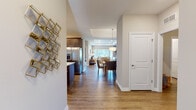 This thoughtfully designed single-floor residence offers a seamless open-concept layout that connects the kitchen, dining, and living areas in a cohesive and functional flow. Warm hardwood-style flooring runs throughout the main living spaces, complemented by neutral wall tones and clean white trim that give the home a bright, polished feel.

The kitchen is a standout feature, showcasing rich dark-toned shaker cabinetry, white quartz countertops, a herringbone tile backsplash, and a full suite of stainless steel appliances including a gas range, dishwasher, and refrigerator with ice dispenser. A central island provides additional prep and seating space.

The dining area sits adjacent to the kitchen and benefits from a pendant light fixture and open shelving, creating a casual yet refined atmosphere. The living room impresses with a tray ceiling, recessed lighting, and a generous bank of windows that flood the space with natural light and offer views of lush greenery outside.

The primary bedroom is a serene retreat, featuring tray ceiling detailing, plush carpeting, and large windows with elegant drapery. Its ensuite bathroom is well-appointed with a double-sink vanity featuring dark wood cabinetry, white countertops, a glass-enclosed walk-in shower, and sleek tile flooring. A second bedroom offers similar comfort and natural light, completing this refined and livable home.