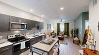 Located at 10000 West Missouri Avenue in Glendale, Arizona, this one-bedroom, one-bathroom residence offers a thoughtfully designed open-concept floor plan. Light wood-style flooring runs throughout the main living areas, lending a clean, contemporary feel to the space.

The kitchen is outfitted with dark espresso cabinetry, light quartz countertops, a tile backsplash, and a full suite of stainless steel appliances including a refrigerator, electric range, and over-the-range microwave. A dining table with bar seating sits adjacent to the kitchen, creating a seamless transition into the living room. The living area features a ceiling fan, a muted sage green accent wall, and a window that allows natural light to fill the room.

The bedroom offers plush carpeting, a ceiling fan, a dedicated closet, and a bright window with views to the outdoors. A second sage green accent wall adds a cohesive design element carried from the living area.

The bathroom includes a dark wood vanity with a white countertop, an oval mirror, and a shower-tub combination. Recessed lighting and light flooring keep the space feeling bright and functional. Overall, the residence presents a modern, cohesive aesthetic with practical and attractive finishes throughout.