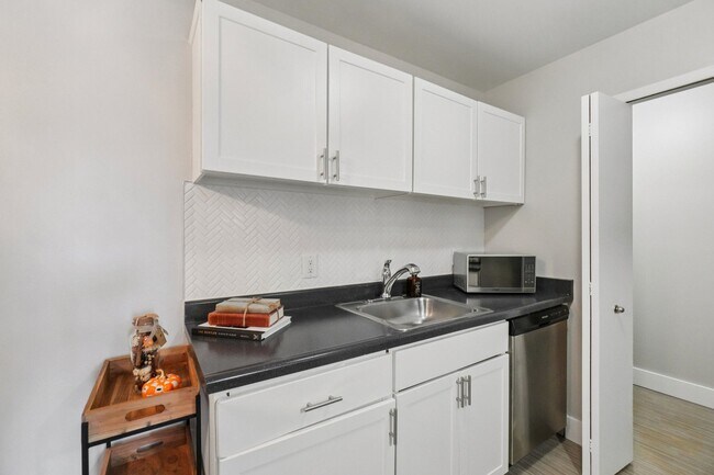 Disfrute de elegantes cocinas con gabinetes blancos brillantes y elegantes encimeras oscuras, operadas profesionalmente por Highlands Vista Group. - Bainbridge Park