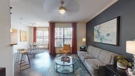 This single-floor residence offers two bedrooms and two full bathrooms within a well-organized, generously sized layout. Dark hardwood flooring flows throughout the main living areas, anchoring the space with warmth and cohesion.

The living room features a bold charcoal accent wall, crown molding, and multiple windows dressed in rich red drapes that invite natural light. A ceiling fan overhead and a glass coffee table complete the inviting arrangement. Adjacent to the living area, the dining nook offers direct access to an exterior door and benefits from a large window, creating a bright setting for meals.

The kitchen is equipped with rich espresso cabinetry, granite-style countertops, a tile backsplash, and black appliances. A breakfast bar with pendant lighting and bar seating connects the kitchen to the main living space.

Both bedrooms feature dark hardwood flooring and windows with natural light. The primary bedroom includes decorative mirrored accents and colorful drapery, while the secondary bedroom offers ample dresser space and a serene, neutral palette.

Each bathroom is finished with dark wood vanity cabinetry, granite-style countertops, large mirrors, and light tile flooring. One bathroom features an extended L-shaped vanity, while the second includes a tub-shower combination.