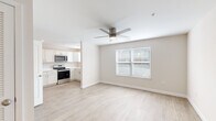 This 1-bedroom, 1-bathroom unit offers a thoughtfully designed single-floor layout that maximizes every square foot. Light wood-style flooring flows consistently throughout the space, contributing to a clean, cohesive aesthetic. The open-concept living area is bright and airy, featuring a ceiling fan, a large window with blinds, and a glass-paned exterior door that brings in natural light and provides outdoor access. The kitchen is efficiently appointed with white shaker-style cabinetry, light countertops, stainless steel appliances including a range, microwave, and dishwasher, and a single-basin sink beneath a window. The bedroom offers a comfortable footprint, complete with a ceiling fan, a window with blinds, and a sliding-door closet with built-in shelving and hanging rods. The bathroom is finished in a clean, neutral palette with a white vanity, light countertop, framed mirror, lighted vanity bar, and wood-style flooring that ties seamlessly into the rest of the unit. Throughout, the space maintains a fresh, move-in-ready appearance with neutral wall tones, crisp white trim, and consistent finishes that create a calm and functional living environment.