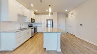 Located at 101 Ascend Loop in Myrtle Beach, South Carolina, this single-floor home offers a thoughtfully designed open-concept layout with contemporary finishes throughout. The kitchen serves as the heart of the home, showcasing crisp white shaker cabinetry, a classic subway tile backsplash, and gleaming granite countertops. A generously sized center island with matching granite provides additional prep space and seating, while pendant lighting overhead adds a stylish focal point. Stainless steel appliances, including a range, microwave, dishwasher, and refrigerator, complete the well-equipped kitchen. Light wood-tone flooring flows seamlessly from the kitchen into the adjacent living and dining areas, where natural light pours in through multiple windows fitted with blinds. A ceiling fan keeps the space comfortable year-round. The bedrooms are carpeted for warmth and comfort, with windows that invite natural light and outdoor views. The primary suite includes direct access to a bathroom featuring a full soaking tub and shower combination, along with a spacious walk-in closet outfitted with wire shelving and built-in organizational racks. An additional walk-in closet elsewhere in the home offers generous storage capacity. The overall aesthetic is clean, bright, and move-in ready, reflecting a cohesive modern design.