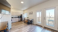 This thoughtfully laid-out 2-bedroom, 2-bathroom residence offers a comfortable and modern living experience across a single floor. The open-concept kitchen and living area serves as the heart of the home, featuring light wood-tone cabinetry, dark countertops, and a full suite of stainless steel appliances including a refrigerator, dishwasher, range with hood, and microwave. Wood-look plank flooring extends throughout the main living areas, lending warmth and continuity to the space. The living room is accented by a striking blue feature wall and opens directly to a private balcony through glass doors, allowing natural light to flow in. A dedicated dining area sits adjacent to the kitchen, completing the open layout. The primary bedroom is generously sized, featuring vaulted ceilings, a ceiling fan, soft carpet flooring, a mirrored sliding closet, and a private ensuite bathroom with a glass-enclosed shower. The second bedroom also offers plush carpet, a ceiling fan, and ample natural light. A second full bathroom includes a tub/shower combination, wood-tone vanity, and dark countertop. A hallway connects the private areas of the home, ensuring a functional and efficient floor plan throughout.
