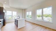 Located at 433 Bishop St NW in Atlanta's vibrant West Midtown neighborhood, this well-appointed 2-bedroom, 2-bathroom residence offers a thoughtfully designed single-floor layout. The open-concept living and kitchen area serves as the heart of the home, bathed in natural light from oversized windows that frame sweeping views of the Atlanta skyline and lush treetops. Light wood-tone flooring runs throughout the main living areas, enhancing the bright and airy atmosphere. The contemporary kitchen is a standout feature, showcasing sleek gray flat-front cabinetry extending to the ceiling, a white subway tile backsplash, stainless steel appliances including a gas range, microwave, and refrigerator, and a large white quartz island with an undermount sink and matte black faucet — ideal for both meal prep and casual dining. The living area flows seamlessly from the kitchen, offering generous space with continued views through multiple large windows. Both bedrooms are finished with plush carpet, large windows providing abundant natural light and open views, and panel-style white doors. The bathrooms continue the modern aesthetic with gray vanities, matte black hardware, and wood-look flooring. A dedicated closet provides additional storage. In-unit laundry is also included, adding to the overall convenience of this well-equipped residence.