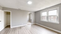 This single-floor unit offers a thoughtfully arranged layout housing four bedrooms, three bathrooms, a kitchen, and a connecting hallway. Throughout the space, light gray walls are paired with light-toned luxury vinyl plank flooring, creating a clean, cohesive aesthetic that maximizes the sense of openness despite the compact footprint.

The primary bedroom is the most spacious of the four, featuring a closet, a distinctive arched doorway that connects to the hallway, and windows that allow natural light to filter in. The remaining bedrooms are similarly finished, each with light-filled windows offering exterior views and closet access, maintaining a consistent and functional design.

The kitchen is equipped with gray shaker-style cabinetry, a granite-look countertop with an undermount sink, and a gas range, providing practical cooking essentials in an efficient layout with light vinyl plank flooring.

The three bathrooms continue the neutral palette, with at least one featuring tiled walls and a soaking tub. The hallway connects the rooms with arch-accented passageways, reinforcing a subtle architectural detail that adds character to the otherwise modern, minimalist interior. Textured ceilings appear in select rooms, adding a classic finish to the overall design. The entry area includes a window overlooking the exterior, welcoming natural light into the space from the moment of entry.