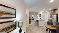 Located at 267–269 Charlotte Hwy in Asheville, NC, this single-floor residence offers a thoughtfully designed open-concept layout that seamlessly connects the kitchen, dining, and living areas. Light-toned hardwood-style flooring runs throughout the main living spaces, creating a clean, cohesive aesthetic.

The kitchen is a standout feature, equipped with stainless steel appliances including a refrigerator, range, and microwave. Rich warm-toned cabinetry provides ample storage, while a large granite-topped island with an undermount sink and bar seating serves as the centerpiece — ideal for both meal prep and casual dining. Pendant lighting above the island adds a polished finishing touch.

The living room offers a comfortable, welcoming atmosphere with recessed lighting and room for generous furnishings. Both bedrooms are carpeted and well-proportioned, with the primary bedroom featuring natural light from a window framed by floor-length drapes. Each bedroom is serviced by its own bathroom, both finished with granite-topped vanities, wood cabinetry, and hardwood-style tile flooring. One bathroom includes a full soaking tub and shower combination.

A dedicated in-unit laundry area with a full-size washer and dryer, topped with additional cabinetry for storage, adds everyday convenience. The unit's neutral color palette and modern finishes throughout create a calm, move-in-ready environment.