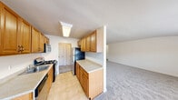 Located at Heatherwood House at Patchogue in Patchogue, NY, this single-floor residence combines practical design with comfortable living spaces. The galley-style kitchen is efficiently laid out with warm oak cabinetry on both sides, light-toned countertops, tile flooring, and stainless steel appliances including a gas range with hood, refrigerator, and built-in microwave. Overhead fluorescent lighting keeps the space bright and functional, and the kitchen opens conveniently toward the living area. The spacious living room features plush wall-to-wall carpeting, a wall-unit air conditioner, baseboard heating, and multiple windows that invite natural light and provide views of the surrounding neighborhood. The bedroom is generously sized with soft carpeting, neutral walls, and ample built-in closet storage with bifold doors, offering both comfort and organization. The bathroom is clean and well-appointed, featuring a tiled floor, a full tub and shower combination with a sliding glass door, a single vanity with storage below, and a large mirror with overhead lighting. Throughout the residence, a neutral color palette and simple, functional finishes create a cohesive and livable atmosphere suited for everyday comfort.
