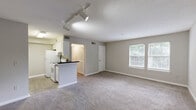 Located at 1994 Bent Creek Way SW in Atlanta, GA, this single-floor, one-bedroom residence offers a functional and comfortable layout across a compact but efficiently arranged floor plan. The combined kitchen and living room serves as the heart of the home, with the living area featuring soft carpeting, neutral gray-beige walls, a textured ceiling, and track lighting that creates a warm and adaptable ambiance. The kitchen is designed in a galley style, with white cabinetry lining both sides, dark granite-style countertops, light hardwood-style flooring, and white appliances including a refrigerator, electric range, and dishwasher — providing a clean, functional cooking space. A hallway connects the main living area to the private bedroom, which is generously proportioned and serves as a peaceful retreat. The bedroom features plush carpeting, neutral tones, and multiple windows fitted with blinds that allow natural light to filter in while maintaining privacy. The en-suite bathroom includes a white vanity with dark countertops and a well-lit mirror. A dedicated closet provides additional storage. Throughout the unit, consistent neutral finishes and soft textures create a cohesive, understated aesthetic suited to a variety of personal styles.