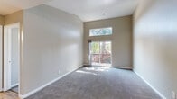 Located at 2005 San Jose Dr in Antioch, CA, this two-bedroom, two-bathroom home offers a thoughtfully laid-out single-floor plan. The living area is a standout, boasting dramatic vaulted ceilings that amplify the sense of openness. A sliding glass door floods the space with natural light and opens onto a private balcony overlooking lush greenery, creating a seamless indoor-outdoor connection. A transom window above the door further enhances the brightness of the room, which is finished with plush wall-to-wall carpeting.

The kitchen is well-appointed with warm honey-toned wood cabinetry, granite-style countertops, and durable wood-look vinyl flooring. Black appliances, including a refrigerator, range, and dishwasher, complement the functional layout with ample upper and lower cabinet storage.

Both bedrooms are carpeted and receive generous natural light through large windows with outdoor views. Two dedicated closets provide practical storage throughout the home. The primary bathroom features a standalone shower, while the second bathroom offers a full tub-shower combination — both include wood-toned vanities with white countertops and wood-look flooring, maintaining a cohesive aesthetic throughout the residence.