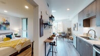 Located at 4186 4th Ave in San Diego's vibrant Hillcrest neighborhood, this single-floor unit showcases a thoughtfully designed open layout that maximizes every inch of space. Light wood-tone flooring runs throughout, complementing the clean white walls and recessed lighting that create a bright, cohesive atmosphere.

The galley-style kitchen is well-appointed with rich walnut-toned cabinetry, stainless steel appliances including a range, microwave, and refrigerator, and a light-colored countertop. Adjacent to the kitchen, a compact bar-height counter with stools serves as a casual dining and workspace area, while open wall-mounted shelving adds functional display space.

The living area benefits from a large window that invites natural light and offers views of the surrounding neighborhood, creating an airy feel. The bedroom features recessed lighting, a corner window, and ample wall space, contributing to a calm and comfortable retreat.

The bathroom is finished in a clean, contemporary style with white subway tile surrounding the bathtub, a single vanity with a large mirror, and wood-look flooring that ties back to the rest of the unit. Overall, the space presents a modern, well-curated environment suited for comfortable urban living.