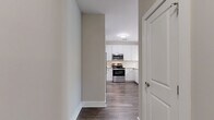 Located at 1824 Defoor Ave NW in Atlanta, GA, this single-story 2-bedroom, 2-bathroom residence offers a thoughtfully designed layout with modern finishes throughout. The open-concept kitchen and living area serves as the heart of the home, where the kitchen stands out with granite countertops, white shaker cabinetry, a classic subway tile backsplash, stainless steel appliances including a gas range and built-in microwave, and a peninsula with seating. Rich hardwood-style flooring flows through the main living areas, complemented by neutral warm-toned walls that create a bright, inviting atmosphere. The living area benefits from natural light streaming through large glass doors with transom windows that frame views of lush greenery. A built-in shelving nook with a lattice detail adds a charming architectural touch. Both bedrooms are carpeted for comfort and served by their own closets with wire shelving systems. Each bathroom features granite-topped white vanities, large mirrors, and wood-style flooring. The primary bedroom is a comfortable retreat with ample square footage. Two hallways provide efficient flow throughout the home, enhancing accessibility between all rooms. This residence combines clean contemporary design with practical, livable spaces in a desirable Atlanta location.