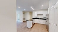 Located at 6801 W Friendly Ave in Greensboro, NC, this single-floor 2-bedroom, 2-bathroom residence offers a clean, modern aesthetic throughout. The open-concept kitchen and living area serves as the heart of the home, featuring crisp white shaker cabinetry, dark granite countertops, a peninsula island, and a full suite of stainless steel appliances — including a refrigerator, range, microwave, and dishwasher — all set atop warm light wood-style flooring. The living area is bright and airy, with a ceiling fan and French doors that invite natural light and provide outdoor access. Both bedrooms are carpeted and equipped with ceiling fans; the primary bedroom is generously sized, with dual closets — including a walk-in — and large windows that bring in natural light. The primary bathroom features a double-sink vanity with dark granite countertops, white cabinetry, and wood-style flooring. The second bathroom offers a single vanity with matching finishes and a shower-tub combination. A dedicated laundry room with side-by-side washer and dryer and wire shelving adds everyday convenience. The hallway connects all rooms with a cohesive, neutral palette throughout.