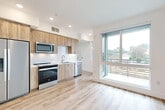 This thoughtfully designed one-bedroom, two-bathroom unit offers a contemporary living experience within a compact but well-utilized floor plan. Light wood-tone luxury vinyl plank flooring runs throughout, creating a cohesive and airy aesthetic across all spaces.

The open kitchen is outfitted with natural wood-grain cabinetry, white quartz countertops, and a full suite of stainless steel appliances, including a refrigerator, range, microwave, and dishwasher. A large floor-to-ceiling sliding glass door and balcony access flood the kitchen and living area with abundant natural light and provide outdoor views of the surrounding neighborhood.

The bedroom features large windows that frame treetop and neighborhood views, complemented by a ceiling fan and clean white walls that enhance the sense of brightness and space.

Both bathrooms are finished to a high standard. The primary bathroom showcases a glass-enclosed walk-in shower clad in full-height marble-style tile with brushed nickel fixtures. The second bathroom includes a wood-grain vanity with a white quartz countertop, a large mirror, and coordinating tile flooring. An in-unit washer is also included within the hallway area, adding practical convenience to this modern unit.