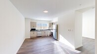 Located at 1707 Element Lane in Sandpoint, Idaho, this single-floor unit offers a thoughtfully designed layout with clean, modern finishes throughout. The space is anchored by a fully equipped kitchen featuring light wood cabinetry, dark stone countertops, stainless steel appliances including a refrigerator, range, dishwasher, and microwave, and a window above the sink that brings in natural light. The hardwood-style flooring runs continuously through the kitchen and into the open living area, creating a cohesive, streamlined aesthetic. Crisp white walls and recessed and flush-mount ceiling lighting keep the space feeling bright and airy. French doors in the living area open to an outdoor patio, allowing natural light to flood the interior and providing a seamless connection to the outside. The bathroom is generously proportioned and designed with accessibility in mind, featuring a floating vanity with a dark countertop, a large mirror with modern wall sconces, and a roll-in shower equipped with grab bars and a fold-down bench seat. The overall ambiance is clean, contemporary, and functional, making this a well-suited space for comfortable everyday living in the heart of Sandpoint.
