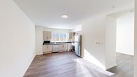 Located at 1707 Element Lane in Sandpoint, Idaho, this single-floor unit offers a thoughtfully designed layout with clean, modern finishes throughout. The space is anchored by a fully equipped kitchen featuring light wood cabinetry, dark stone countertops, stainless steel appliances including a refrigerator, range, dishwasher, and microwave, and a window above the sink that brings in natural light. The hardwood-style flooring runs continuously through the kitchen and into the open living area, creating a cohesive, streamlined aesthetic. Crisp white walls and recessed and flush-mount ceiling lighting keep the space feeling bright and airy. French doors in the living area open to an outdoor patio, allowing natural light to flood the interior and providing a seamless connection to the outside. The bathroom is generously proportioned and designed with accessibility in mind, featuring a floating vanity with a dark countertop, a large mirror with modern wall sconces, and a roll-in shower equipped with grab bars and a fold-down bench seat. The overall ambiance is clean, contemporary, and functional, making this a well-suited space for comfortable everyday living in the heart of Sandpoint.