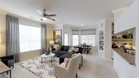 This single-floor residence features a thoughtfully designed layout that maximizes comfort and functionality. The living area serves as the heart of the home, showcasing crown molding, plush carpeting, and a ceiling fan that enhances the bright, airy atmosphere. Multiple windows, including a charming bay window, flood the space with natural light while Roman shades and curtain panels provide flexible privacy options.

The open-concept design seamlessly connects the living and dining areas, creating an inviting space well-suited for both relaxing and entertaining. Built-in shelving adds both character and practical storage to the living room, while recessed lighting complements the overall illumination. The neutral color palette of warm whites and soft grays provides a versatile backdrop that adapts easily to various décor styles.

The bay window area naturally accommodates a dedicated dining space, adding a cozy, defined nook within the open floor plan. Overall, the residence balances classic architectural details with modern comfort, creating a welcoming and functional living environment.