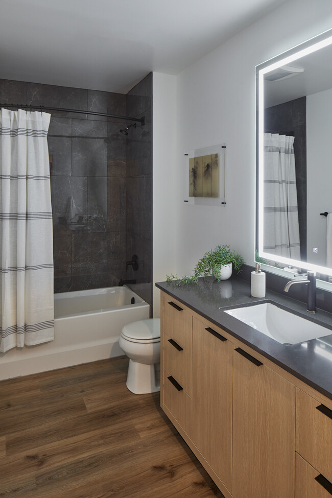 Baño del apartamento con piso estilo madera y espejo de tocador LED. - Griffis Seattle Waterfront