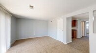 This one-bedroom, one-bathroom residence at 65 W Summerset Ln in Buffalo, NY offers a well-organized, single-floor layout designed for comfortable everyday living. The living room is a bright, open space featuring neutral gray walls, plush wall-to-wall carpeting, and a sliding glass door that floods the room with natural light and provides outdoor views. A ceiling fan with a light fixture adds comfort to the adjacent dining area, which flows seamlessly into the kitchen. The kitchen is well-appointed with rich, warm-toned wood cabinetry, dark granite-style countertops, a double sink, hardwood-style flooring, and white appliances including a refrigerator and range. The bedroom offers a comfortable footprint with carpet flooring, a natural window view, and a sliding wood-panel closet for storage. A second closet and a utility room provide additional storage throughout the home. The bathroom features a tiled tub-shower combination, a white vanity, and hardwood-style flooring. A hallway connects the rooms cohesively, completing this practical and neatly maintained floor plan suited for single occupancy or couples.