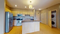 This single-floor residence offers a thoughtfully designed layout that balances functionality and comfort. The kitchen serves as the heart of the unit, showcasing light maple cabinetry, granite-style countertops, and a full suite of stainless steel appliances including a refrigerator, electric range, built-in microwave, and dishwasher. A central island with a pendant light overhead provides additional counter space and a natural gathering point. Light bamboo-style flooring runs throughout the kitchen and living areas, lending warmth and continuity to the open space.

The bedrooms are finished with rich, wood-toned laminate flooring and neutral taupe walls, creating a calm and versatile environment. Each room benefits from natural light provided by windows with blinds, offering both brightness and privacy.

The unit includes multiple bathrooms, each finished with warm earth-toned tile flooring and clean, modern vanities featuring light wood cabinetry and brushed hardware. The primary bathroom offers a dual-sink vanity with overhead lighting and an adjacent closet, while secondary bathrooms include single-sink vanities and bathtub combinations. Throughout the space, a cohesive neutral color palette and consistent finishes create a polished, move-in-ready atmosphere.