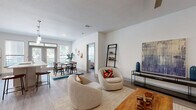 This well-appointed 2-bedroom, 2-bathroom residence at 3333 Weslayan Street in Houston's sought-after 77027 corridor offers a thoughtfully designed single-floor layout with modern finishes throughout. The open-concept living area features light wood-tone flooring, a ceiling fan, and a welcoming entryway with double doors. The living room flows seamlessly into the dining area, which benefits from large windows that invite abundant natural light and garden views. The kitchen is a standout feature, boasting gray shaker cabinetry, a center island with bar seating, pendant lighting, stainless steel appliances, and a built-in desk nook — ideal for working from home. The primary bedroom is a comfortable retreat with a ceiling fan, large window with sheer curtains, and wood-look flooring. The en-suite primary bathroom is elegantly finished with a dual-sink vanity, white quartz countertops, subway tile shower surround, and direct access to a generously sized walk-in closet with built-in wire shelving. A second bedroom and additional full bathroom provide flexibility for guests or roommates. The dedicated laundry room houses a full-size washer and dryer with overhead shelving. A hallway connects all areas efficiently, completing this well-organized and stylish home.