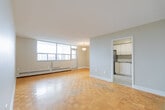 Located at 100 Queen St N in the heart of Kitchener, Ontario, this one-bedroom, one-bathroom unit offers a practical and well-appointed layout across a single floor. The living area is bright and open, featuring classic parquet wood flooring throughout and neutral grey walls that create a clean, versatile backdrop. Large windows allow natural light to pour in while offering views of the surrounding neighbourhood, and baseboard heating runs along the exterior walls to ensure year-round comfort.

The kitchen is thoughtfully updated, showcasing white cabinetry with sleek hardware, grey countertops, a white subway tile backsplash, and a stainless steel electric range with an overhead ventilation hood — a functional space well-suited for everyday cooking.

The bedroom is a comfortably sized private retreat, continuing the warm parquet flooring found throughout the unit. The bathroom features a full soaking tub with a shower, tiled surround in white and taupe accents, and a safety grab bar, adding a practical and accessible touch.

An entry hallway provides a defined transition into the living space. The overall aesthetic is clean and understated, making this a functional unit in a well-connected Kitchener location.