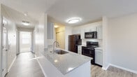 Located at 6049 Rings Ave in Grove City, Ohio, this single-floor residence offers a clean, modern aesthetic throughout. The open-concept living and dining area is anchored by durable wood-style plank flooring, neutral-toned walls, and a textured ceiling, with multiple windows fitted with blinds that allow natural light to fill the space. A peninsula-style kitchen connects seamlessly to the living area, showcasing gray shaker cabinetry, granite-look countertops, a stainless steel sink, and black appliances including a refrigerator, range, microwave, and dishwasher — providing both style and functionality. A dedicated hallway leads to the private areas of the home. The bedroom is generously sized, featuring plush carpet flooring and dual windows that offer views of the surrounding neighborhood. A large walk-in closet with wire shelving provides ample storage. Two full bathrooms serve the home, each equipped with wood-style plank flooring, vanities with stone-look countertops, gray cabinetry, and a full tub-shower combination. The overall design maintains a consistent, contemporary palette of soft neutrals, creating a bright and cohesive living environment throughout.