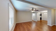 Located in Lafayette, Louisiana, this well-appointed one-bedroom, one-bathroom residence offers a thoughtfully designed single-floor layout across a comfortable footprint. Warm hardwood-style flooring flows consistently through the living room, dining area, and kitchen, lending a cohesive and inviting character to the main living spaces. The living room is generously sized, featuring an exposed ceiling beam, a ceiling fan with integrated lighting, and natural light from multiple windows fitted with white blinds. Neutral, warm-toned walls throughout create a calm and versatile backdrop. The dining area is accented by a brushed nickel chandelier and benefits from its own window, enhancing the sense of brightness. The galley-style kitchen is efficiently organized with rich dark cabinetry, light granite-look countertops, black appliances including a range, microwave, and refrigerator, along with a stainless steel sink — all illuminated by a window at the far end. The spacious primary bedroom is carpeted for comfort and includes a ceiling fan with light, a window with natural light, and ample wall space. The bathroom offers a full tub-shower combination with a curved curtain rod and brushed nickel fixtures, completing this functional and well-maintained residence.