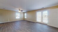 Located at 705 Walnut Ridge Dr in Duquesne, Missouri, this single-floor home offers a thoughtfully designed, open layout with consistent hardwood-style flooring throughout. The spacious living area is bathed in natural light from multiple windows and a set of French doors that lead to the outdoors, creating a bright and airy atmosphere. A ceiling fan with integrated lighting provides comfort and functionality to the main living space.

The kitchen is a standout feature, equipped with dark espresso-toned cabinetry, granite-style countertops, black appliances including a refrigerator, stove, and built-in microwave, and a peninsula that serves as a natural divider between the kitchen and dining area. The adjacent dining space is accented by an elegant chandelier, adding a refined touch.

The layout also includes a generously sized room with a built-in closet system and French door access, offering flexible use as a primary bedroom or additional living space. The bathroom features the same dark cabinetry as the kitchen, a wide vanity with a granite-style countertop, a large mirror, and wood-look tile flooring, maintaining a cohesive design aesthetic throughout. Clean white trim and neutral wall tones tie the entire home together for a polished, move-in-ready feel.