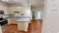 Located at 5202 Auburn St in Lubbock, Texas, this single-floor home offers a well-planned layout that maximizes every square foot. The open-concept kitchen and living area forms the heart of the home, featuring warm hardwood-style flooring, light maple cabinetry, granite-style countertops, and stainless steel appliances including a range and built-in microwave. A peninsula with pendant lighting provides additional prep space and a natural divider between the kitchen and living area, which benefits from natural light through a front-facing window. Crown molding accents the kitchen and living spaces, adding a refined architectural touch. A dedicated laundry closet, conveniently positioned just off the kitchen, houses a full-size washer and dryer. The generously sized bedroom offers plush carpeting, a ceiling fan, and two windows that invite natural light. Multiple closets, including what appear to be walk-in storage spaces, provide ample organization options. The bedroom's neutral tones and soft carpet create a calm, restful atmosphere. Throughout the home, consistent neutral wall colors, white trim, and six-panel interior doors contribute to a clean, cohesive aesthetic.
