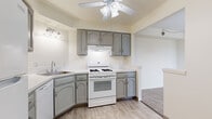 Located at 9333 N Church Dr in Parma Heights, Ohio, this single-floor unit offers a well-organized layout designed for comfortable everyday living. The expansive living room is finished with plush wall-to-wall carpeting and features a large sliding glass door fitted with vertical blinds, allowing an abundance of natural light to fill the space while providing direct access to a private balcony with outdoor views. The layout flows seamlessly into additional rooms via a carpeted hallway. The kitchen is outfitted with grey cabinetry, light countertops, and wood-look tile flooring. It includes a gas range, refrigerator, dishwasher, and a corner sink, all accented by a ceiling fan overhead. The open pass-through connects the kitchen to the adjacent living areas, enhancing the sense of openness. The bedroom offers generous proportions with soft carpeting, neutral walls, and a dedicated closet with built-in shelving for ample storage. The bathroom is neatly appointed with large-format tile flooring, a tiled walk-in shower with a built-in niche and grab bars, and a white vanity. Throughout the unit, a consistent warm neutral palette and clean finishes create a bright, functional, and move-in-ready environment.