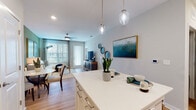 This single-story 1-bedroom residence in Jacksonville, FL (32258) offers a thoughtfully designed open-concept floor plan with cohesive finishes throughout. The kitchen serves as a central hub, featuring white shaker cabinetry, a herringbone tile backsplash, stainless steel appliances, open shelving, and a white-topped island with seating for two, illuminated by elegant glass pendant lights. Light wood-style flooring flows seamlessly through the main living areas, enhancing the sense of continuity and space.

The living area is anchored by a sage green accent wall adorned with botanical artwork, large windows that invite abundant natural light, and a ceiling fan overhead. It connects effortlessly to a dedicated dining space, creating a versatile and welcoming environment. The bedroom features a bold dark accent wall, large windows with outdoor views of lush greenery, wood-style flooring, and a ceiling fan. The bathroom is finished with a white undermount vanity, subway tile tub surround, and brushed nickel hardware, maintaining a clean, modern aesthetic throughout the residence.